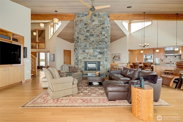 living room featuring a fireplace, a towering ceiling, beamed ceiling, and wood finished floors