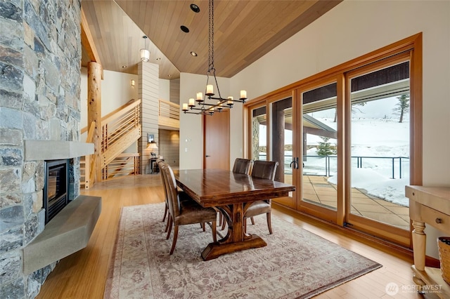 dining area with wooden ceiling, light wood-style flooring, stairs, a fireplace, and high vaulted ceiling