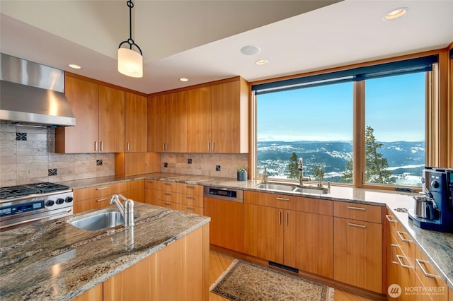 kitchen featuring light stone counters, stainless steel range, a sink, and wall chimney range hood