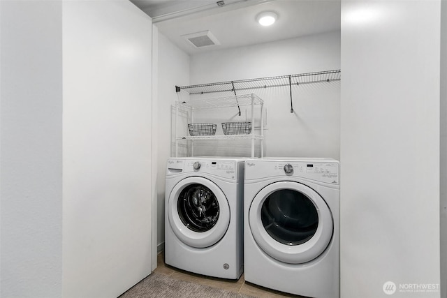 washroom featuring washing machine and dryer, laundry area, light tile patterned flooring, and visible vents