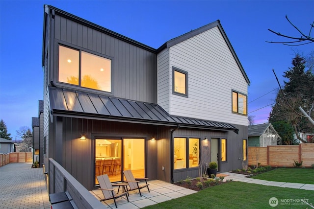 rear view of property featuring a yard, a patio, fence, and a standing seam roof