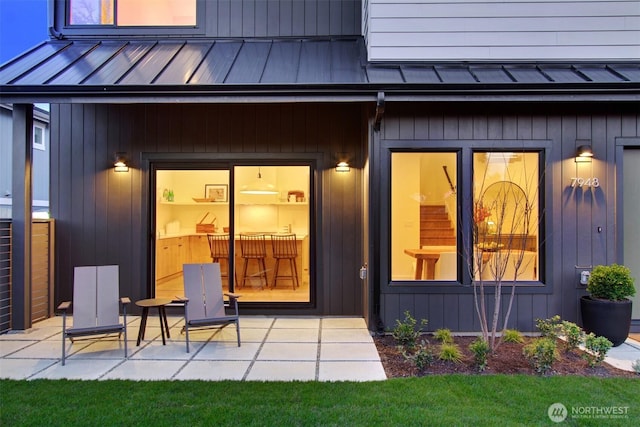 entrance to property with a standing seam roof, a patio, and metal roof