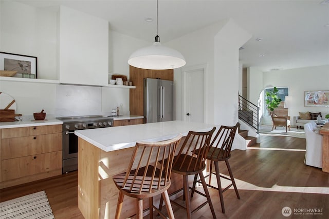 kitchen featuring dark wood-style floors, a kitchen island, light countertops, a kitchen bar, and high quality appliances