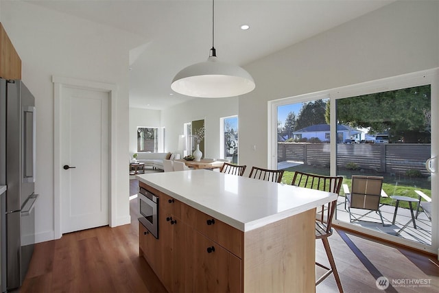 kitchen featuring a kitchen island, a kitchen bar, recessed lighting, wood finished floors, and stainless steel appliances