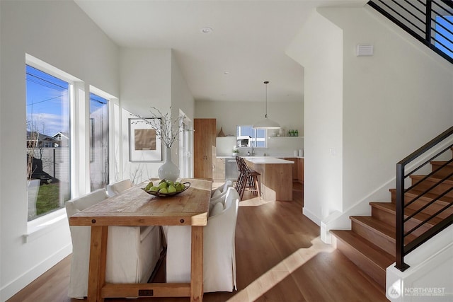 dining room featuring stairway, baseboards, and wood finished floors