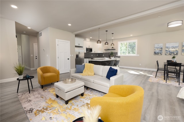 living area featuring recessed lighting, baseboards, visible vents, and light wood finished floors