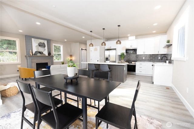 dining area with light wood finished floors, recessed lighting, a fireplace, and baseboards