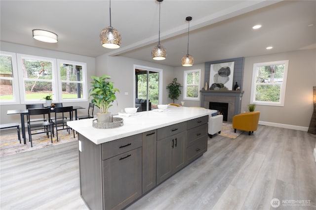 kitchen with a fireplace, light countertops, hanging light fixtures, and light wood finished floors