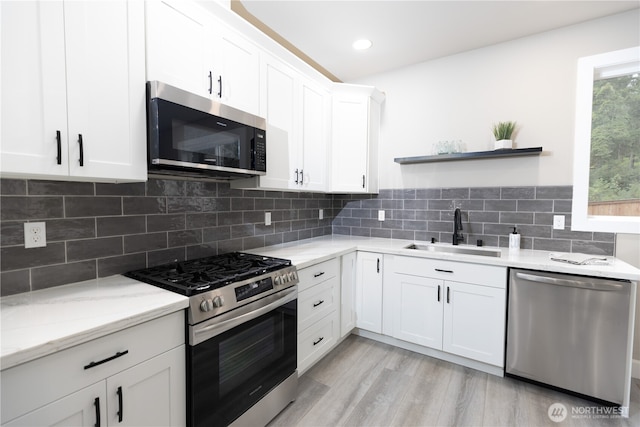 kitchen with open shelves, stainless steel appliances, white cabinets, a sink, and light wood-type flooring