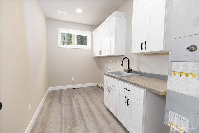 washroom featuring washer hookup, light wood finished floors, cabinet space, a sink, and baseboards