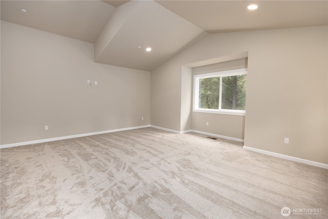 empty room with lofted ceiling, baseboards, and light colored carpet