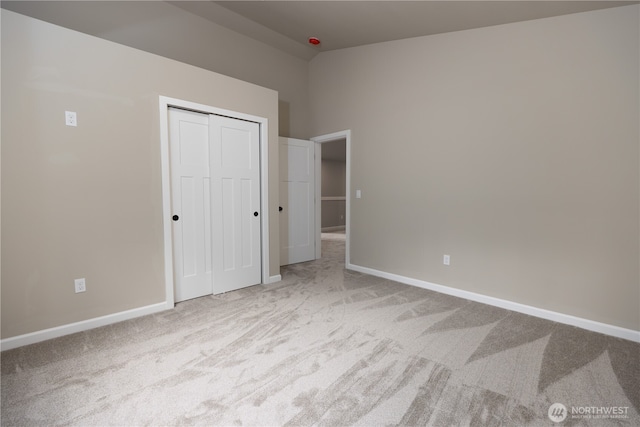 unfurnished bedroom featuring light carpet, baseboards, and a closet