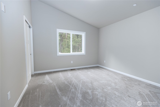 carpeted spare room with lofted ceiling and baseboards