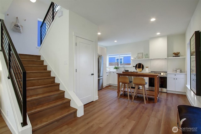 dining room with recessed lighting, wood finished floors, and stairs