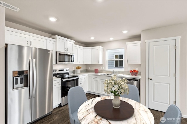 kitchen with a sink, visible vents, white cabinetry, light countertops, and appliances with stainless steel finishes