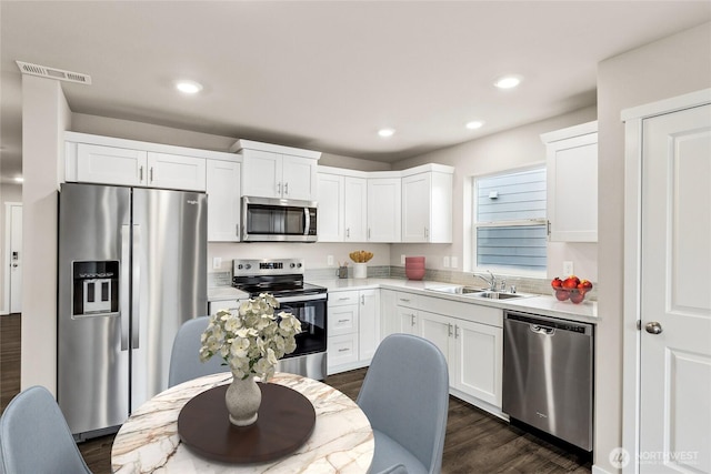 kitchen with light countertops, visible vents, appliances with stainless steel finishes, white cabinets, and a sink