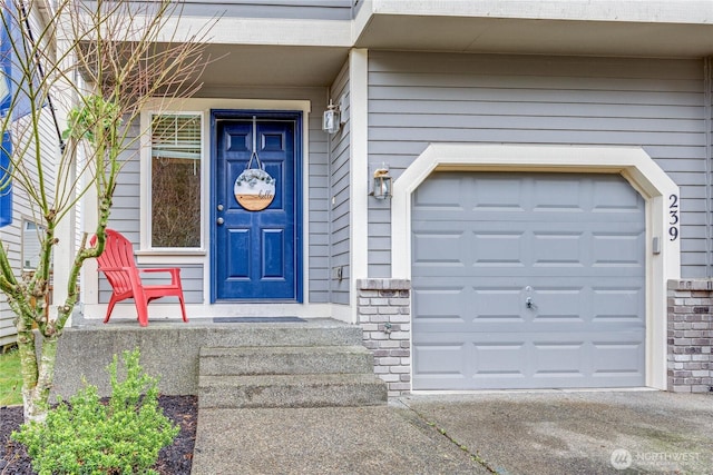 doorway to property with a garage, driveway, and brick siding