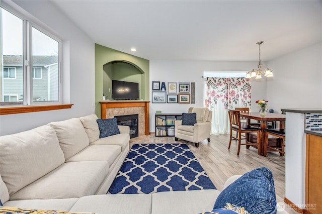 living room featuring light wood finished floors, a tiled fireplace, recessed lighting, and an inviting chandelier