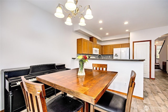 dining room with light wood-type flooring, arched walkways, and recessed lighting