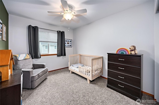 bedroom with a nursery area, ceiling fan, carpet, and baseboards