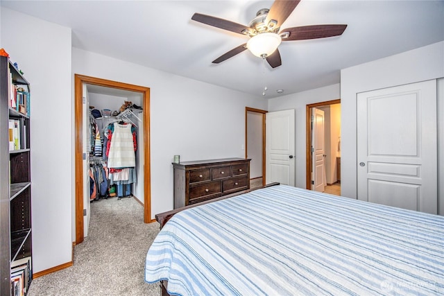 bedroom with ceiling fan, light colored carpet, baseboards, a spacious closet, and a closet