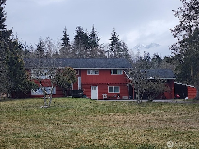 back of property with entry steps and a lawn