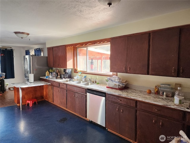 kitchen with a sink, a textured ceiling, stainless steel appliances, and light countertops