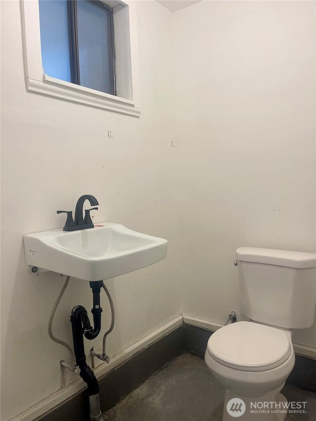 bathroom with concrete floors, a sink, toilet, and baseboards