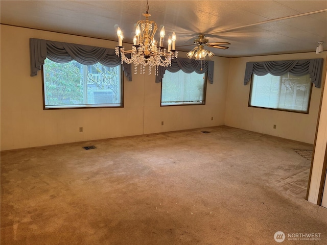 carpeted empty room with a wealth of natural light, visible vents, and an inviting chandelier