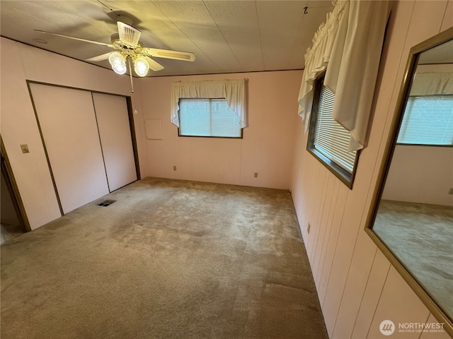 unfurnished bedroom featuring visible vents, multiple windows, and light carpet