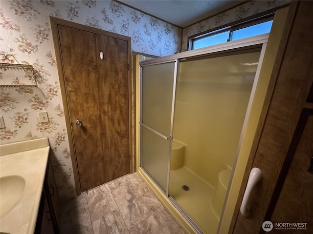 full bathroom featuring a shower stall, vanity, and wallpapered walls