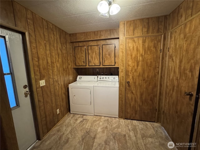 laundry room featuring cabinet space, wooden walls, and independent washer and dryer