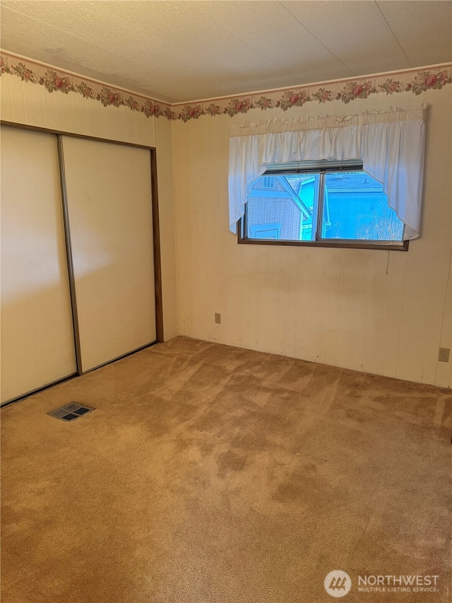 unfurnished bedroom with carpet floors, a closet, and visible vents