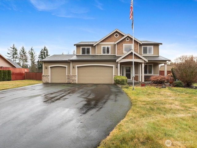 view of front of house featuring aphalt driveway, a front yard, stone siding, and fence