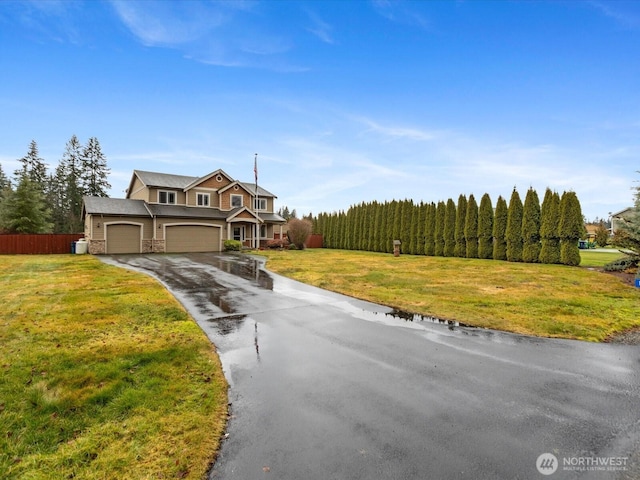 view of front of property featuring a garage, driveway, a front yard, and fence