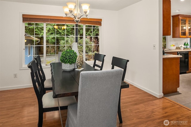 dining area with baseboards, a notable chandelier, and light wood finished floors