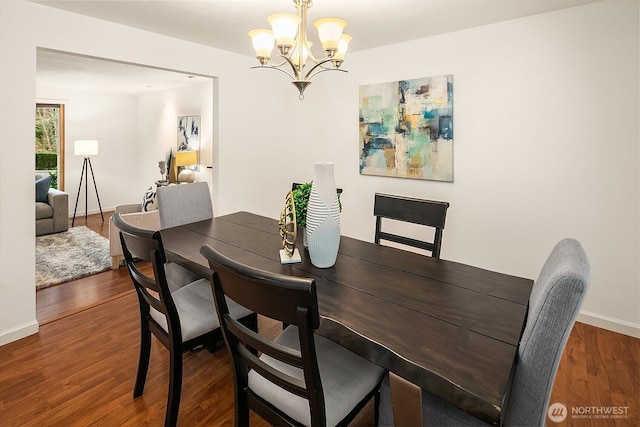 dining room with a notable chandelier, baseboards, and wood finished floors