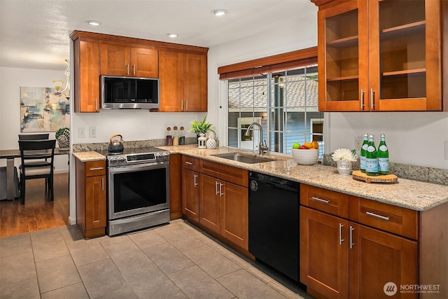 kitchen featuring a sink, brown cabinetry, light stone countertops, and stainless steel appliances