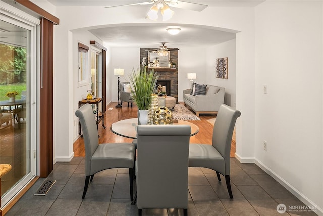 dining area with visible vents, a fireplace, baseboards, and a ceiling fan