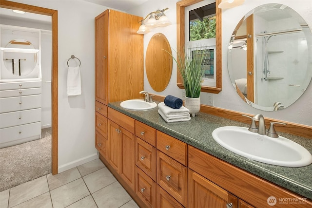 bathroom with double vanity, a shower with door, tile patterned floors, and a sink