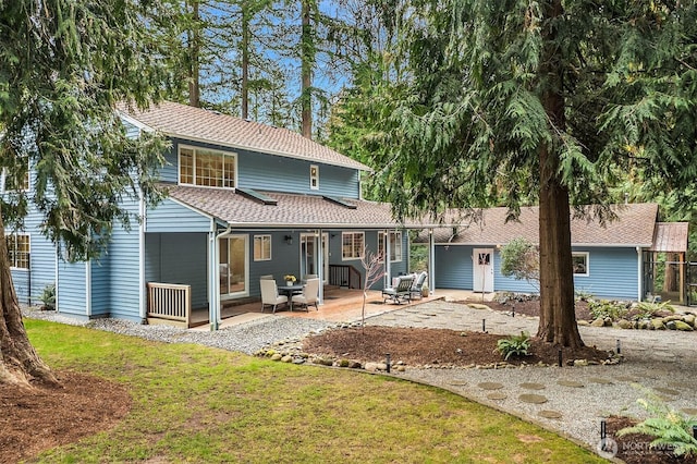 back of property featuring a yard, a patio, and roof with shingles