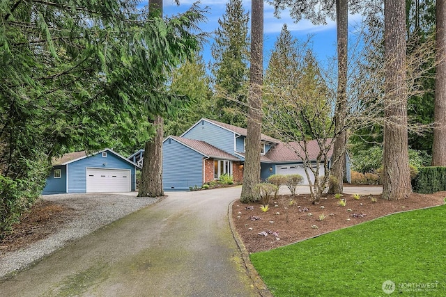 view of front of home with an outdoor structure, brick siding, a garage, and driveway