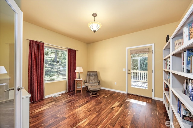 sitting room with plenty of natural light, wood finished floors, visible vents, and baseboards