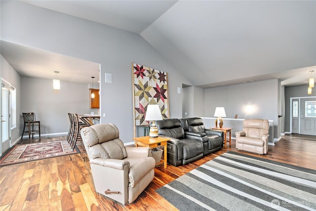 living area with vaulted ceiling, wood finished floors, and baseboards