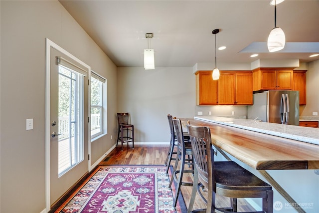 kitchen featuring brown cabinets, plenty of natural light, light countertops, and freestanding refrigerator