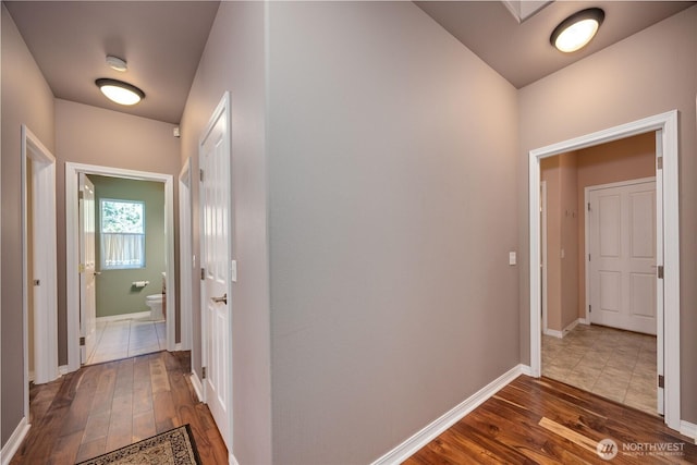 corridor featuring baseboards and wood finished floors