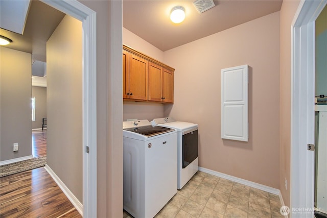 washroom with cabinet space, baseboards, visible vents, and separate washer and dryer