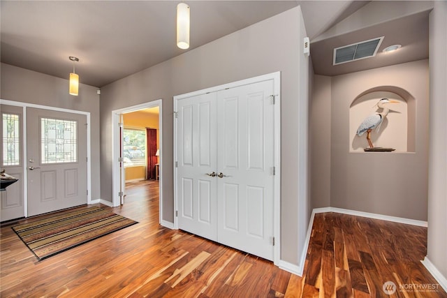 entrance foyer with baseboards, visible vents, and wood finished floors