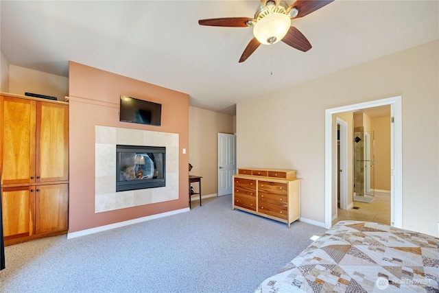 unfurnished bedroom with connected bathroom, light colored carpet, a ceiling fan, baseboards, and a tiled fireplace