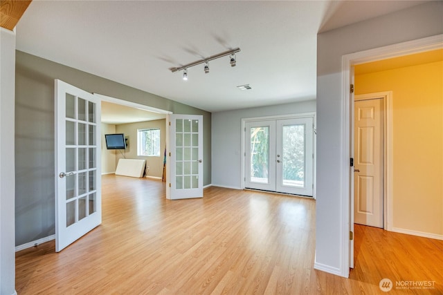 interior space featuring light wood finished floors, baseboards, track lighting, and french doors